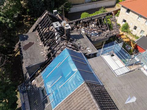 Die Feuerwehr konnte ein komplettes Übergreifen auf das Nachbarhaus verhindern. Auf der Drohnenaufnahme sieht man das teils provisorisch abgedichtete Ziegeldach.