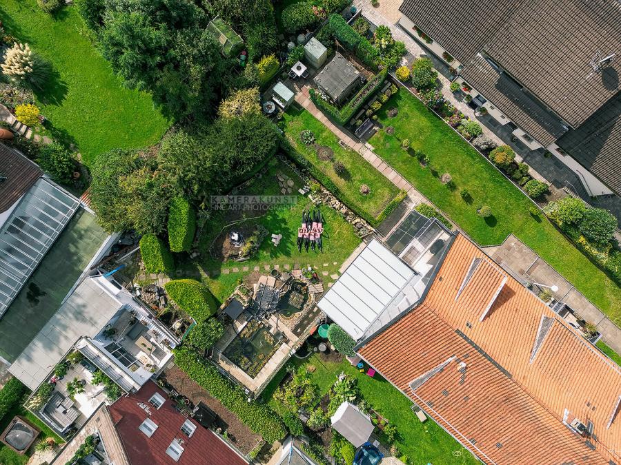 Drohnen-Luftaufnahme aus der Vogelperspektive von ganz weit oben: Fotoshooting mit Freundinnen bei Familienfeier im Garten.