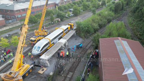 Drohnenaufnahme bei leichtem Regen: Der Transrapid wird vom Schwerlasttransporter angehoben.